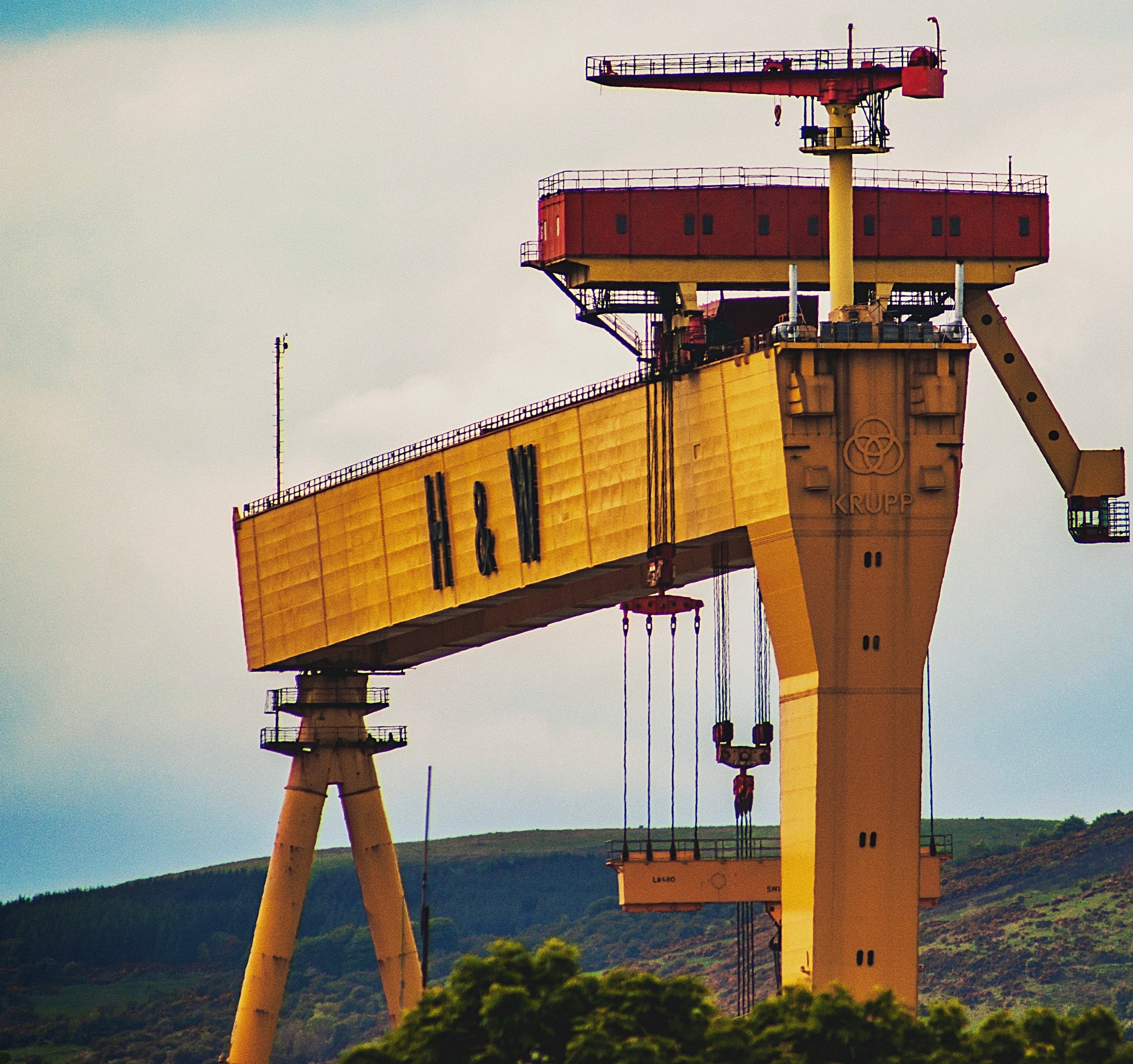 A large yellow crane with 'H&W' and 'KRUPP' text in an industrial setting.